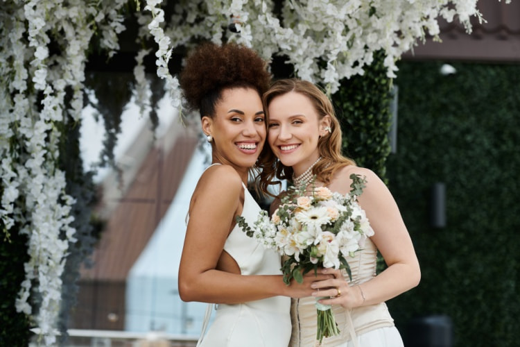 two brides stand together smiling on their wedding day